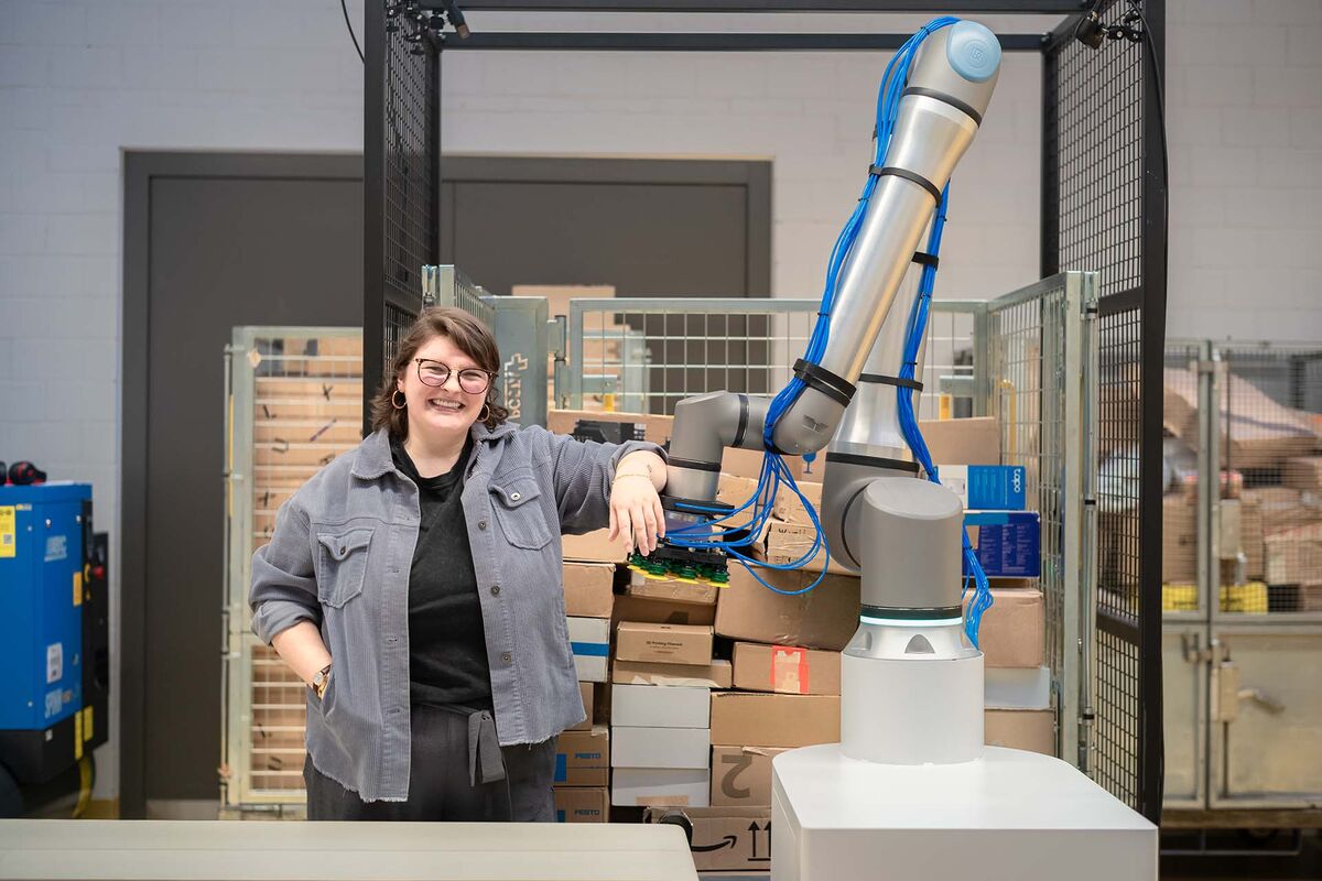 An engineer leaning on a Flinkbot arm